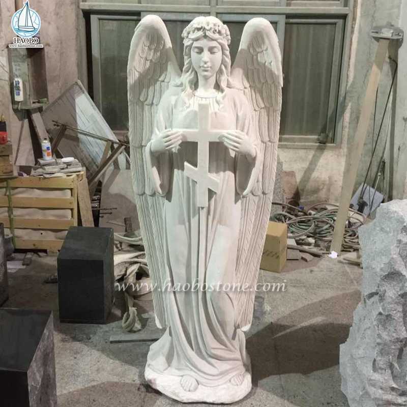 Biały marmurowy krzyż z rzeźbą stojącego anioła

